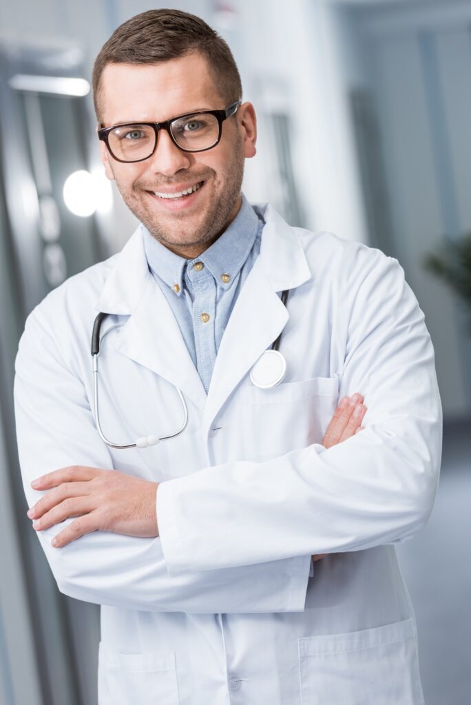 Happy doctor in glasses standing with crossed arms